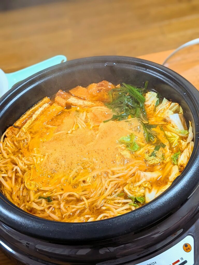 赤から鍋スープでたくさんの野菜やホルモンが煮込まれている様子