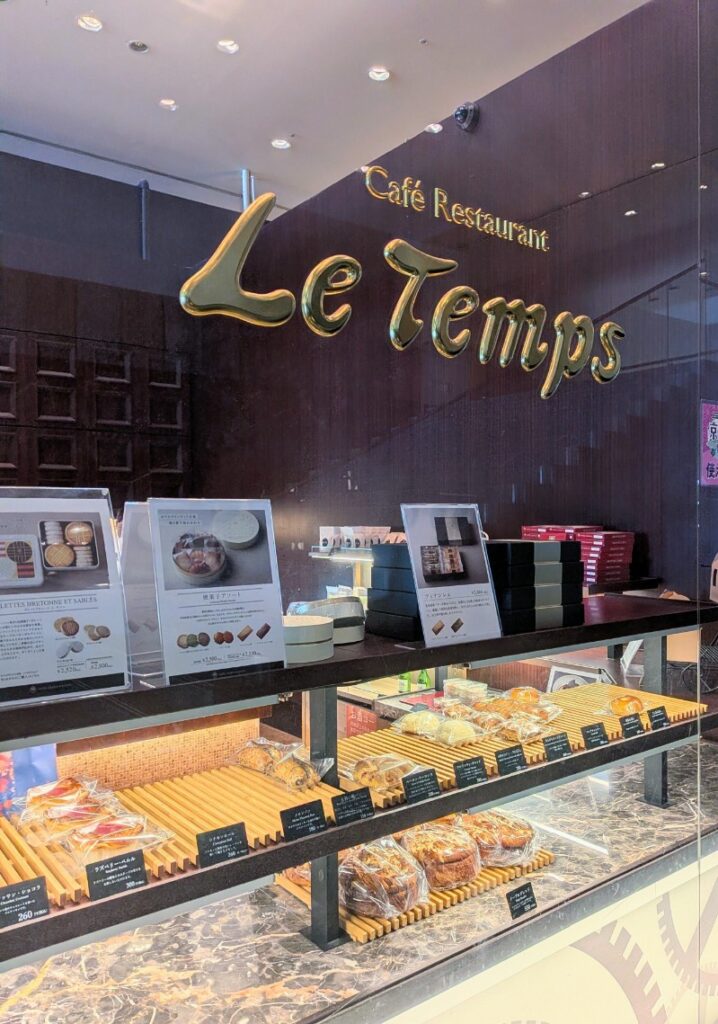 Le Tempsのゴールドのロゴと、美しくディスプレイされたパンや焼き菓子が並ぶショーケースの様子