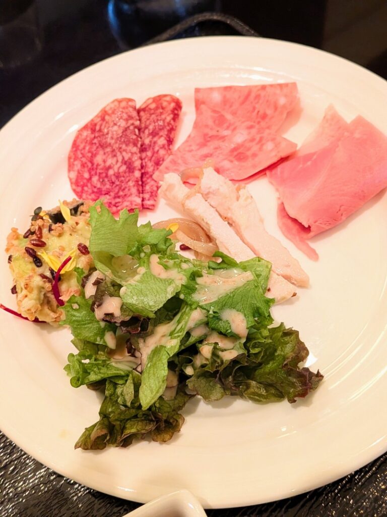 サラダ、ハム、サラミなどが盛られた前菜のプレート